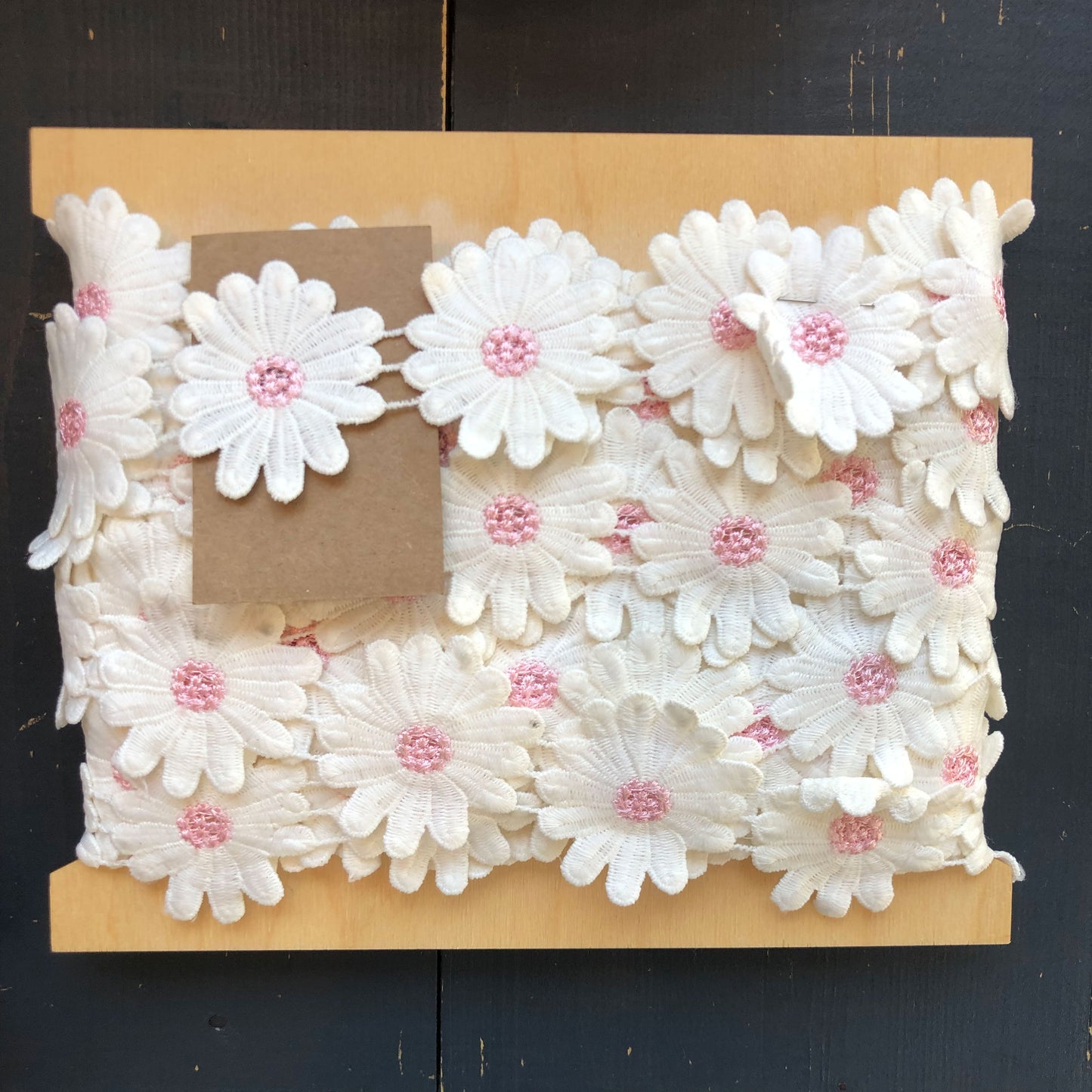 Breng een vleugje vrolijkheid in je creaties met deze charmante sierband vol witte madeliefjes. Elke bloem is fijn afgewerkt met een zachtroze hartje, wat zorgt voor een speels en lief effect.