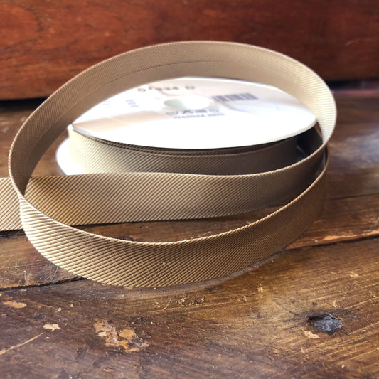 Biasband in een beige kleur met een schuine streep motief erin verwerkt. 