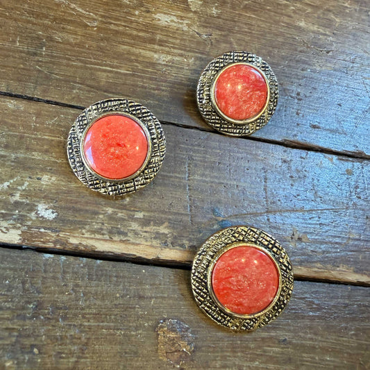 Deze bijzondere knoop combineert een warme goudkleurige rand met een sprankelende zalmroze kern.