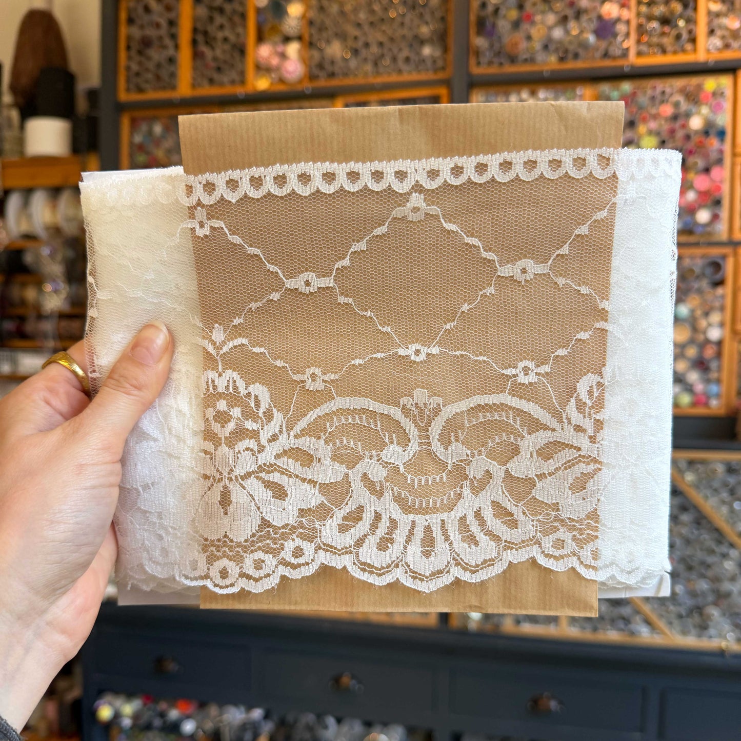 Dit verfijnde witte kant van 15 cm breed heeft een elegante en luchtige uitstraling. Het delicate patroon en de lichte transparantie geven elk ontwerp een zachte, romantische touch.