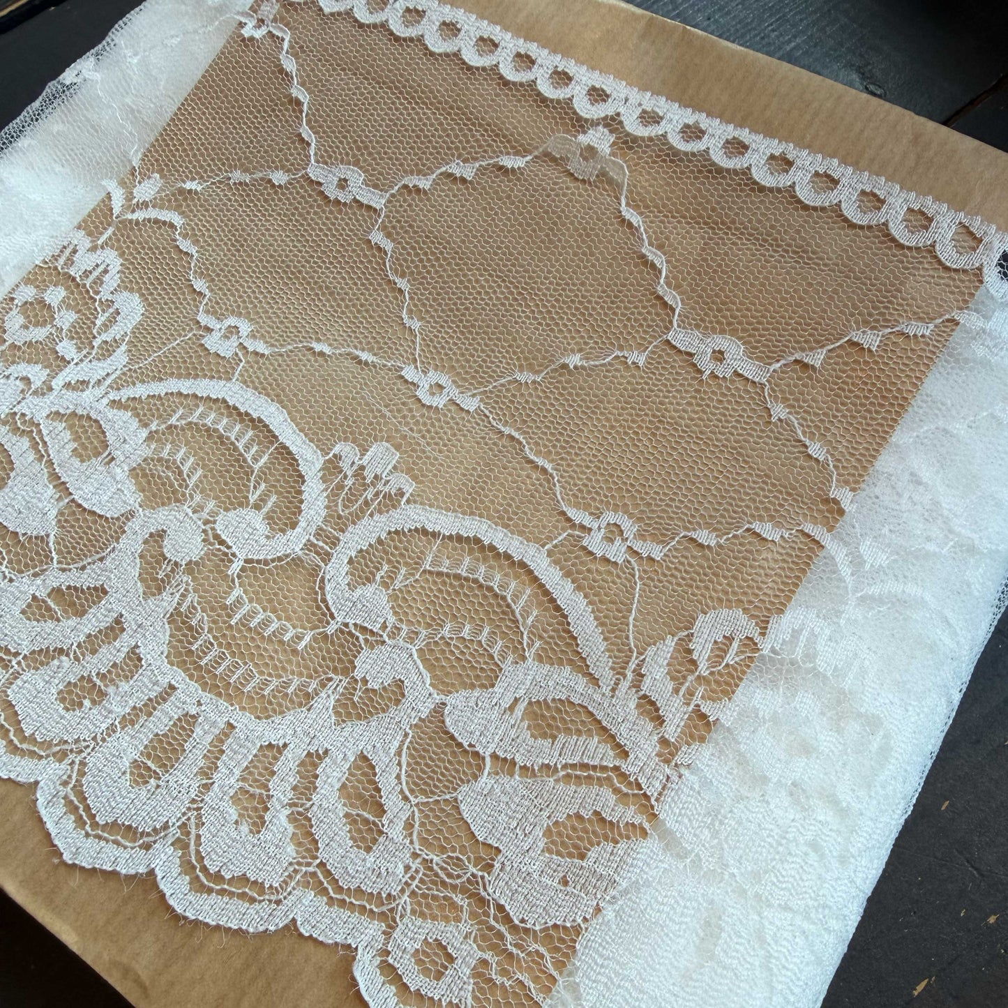 Dit verfijnde witte kant van 15 cm breed heeft een elegante en luchtige uitstraling. Het delicate patroon en de lichte transparantie geven elk ontwerp een zachte, romantische touch.