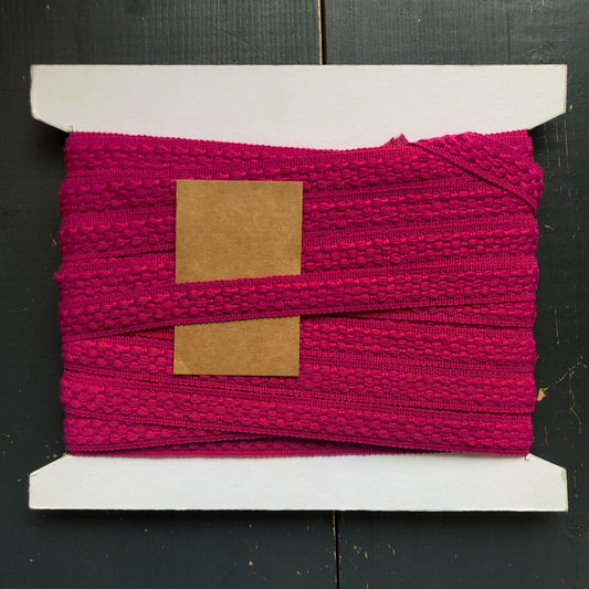 Deze opvallende sierband in fuchsiaroze is perfect voor wie durft! De band is zacht en heeft een subtiel structuurwerkje met een speels patroon. 