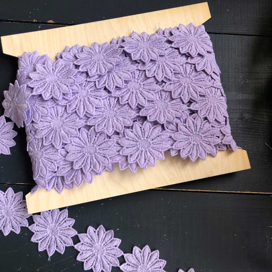 Dit bijzondere sierband is versierd met grote, sierlijke bloemen in een zachte lila tint. De bloemen staan los van elkaar waardoor het band meteen in het oog springt.