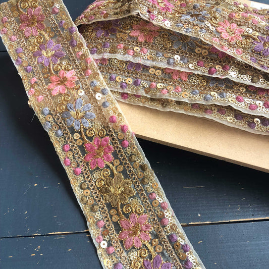 Dit prachtige sierband in lavendeltinten is rijkelijk versierd met geborduurde bloemen en sprankelende pailletten. 