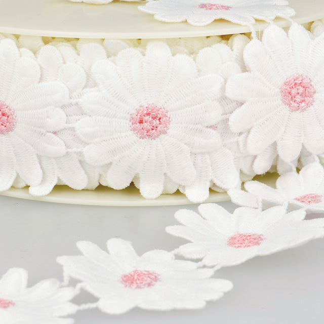 Breng een vleugje vrolijkheid in je creaties met deze charmante sierband vol witte madeliefjes. Elke bloem is fijn afgewerkt met een zachtroze hartje, wat zorgt voor een speels en lief effect.